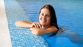 Portrait of happy smiling brunette woman in white swimsuit relaxing in swimming pool and looking in camera Royalty Free Stock Photo