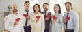 Happy smiling business people holding red hearts in hands standing together in a row in office Royalty Free Stock Photo