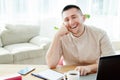 Portrait of happy smiling businessman sitting at wood desk with notepat and laptop computer in modern office and looking at camera Royalty Free Stock Photo