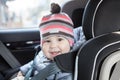 Portrait of happy and smiling Caucasian infant sitting in baby car seat on back of the car