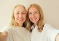 Portrait of happy smiling caucasian middle aged mother or sister and adult daughter stretching her hands for taking selfie with Royalty Free Stock Photo