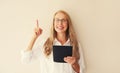 Portrait of happy smiling caucasian middle-aged woman employee with tablet computer or folder with documents and pointing her