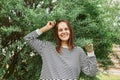 Portrait of happy smiling cheerful woman wearing striped shirt standing with raised arms and satisfied facial expression near Royalty Free Stock Photo