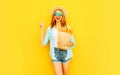 Portrait happy smiling cool girl holding paper bag with long white bread baguette, wearing straw hat, shorts on colorful yellow Royalty Free Stock Photo