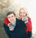 Portrait happy smiling couple in winter park, man giving piggyback ride to woman on snowy forest background Royalty Free Stock Photo