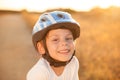 Portrait of happy smiling cute little caucasian boy in blue sport helmet and white shirt on summer warm sunset outdoors Royalty Free Stock Photo