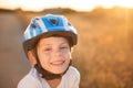 Portrait of happy smiling cute little caucasian child in blue sport protective helmet and white shirt on summer sunset outdoors Royalty Free Stock Photo