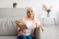 Happy older woman having rest at home, reading book Royalty Free Stock Photo