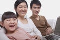 Portrait of happy smiling family sitting on the sofa using laptop, looking at camera, studio shot Royalty Free Stock Photo