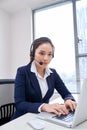 Portrait of happy smiling female customer support phone operator at workplace. Asian Royalty Free Stock Photo