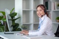 Portrait of happy smiling female customer support phone operator at workplace. Asian Royalty Free Stock Photo