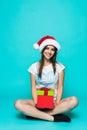 Portrait of a happy smiling girl in dress holding present box sitting on the floor over green background Royalty Free Stock Photo