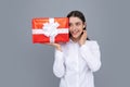 Portrait of a happy smiling girl holding present box and isolated over gray background. Royalty Free Stock Photo