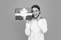 Portrait of a happy smiling girl holding present box and isolated over gray background. Royalty Free Stock Photo