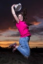 Portrait of happy smiling girl jumping in the evening against colorful sky background with clouds at sunset Royalty Free Stock Photo