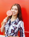 Portrait happy smiling girl with sweet caramel lollipop having fun over red