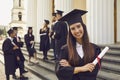 Graduate girl with a diploma in her hands on the background of her classmates. Royalty Free Stock Photo