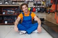 Portrait of happy smiling hardware store worker with spanner sitting on floor Royalty Free Stock Photo