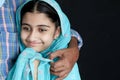 Portrait of happy smiling Indian Muslim girl child in India traditional dress wearing hijab scarf hugging her father on black Royalty Free Stock Photo