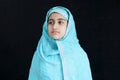 Portrait of happy smiling Indian Muslim girl child in India traditional dress wearing hijab scarf standing on black background. Royalty Free Stock Photo