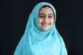 Portrait of happy smiling Indian Muslim girl child on India traditional dress wearing hijab scarf standing in black background. Royalty Free Stock Photo