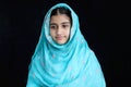 Portrait of happy smiling Indian Muslim girl child on India traditional dress wearing hijab scarf standing in black background. Royalty Free Stock Photo