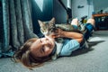 Portrait of a Happy smiling kid at home playing with a kitty cat. Caucasian boy lying on a carpeted floor holding his Royalty Free Stock Photo