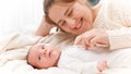 Portrait of happy smiling and laughing young mother tickling and playing with little baby son in bed. Concept of family Royalty Free Stock Photo