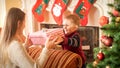 Portrait of happy smiling little boy giving big box with Christmas present to his young mother Royalty Free Stock Photo