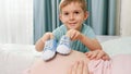 Portrait of happy smiling little boy playing with small baby boots and pregnant mother lying on bed at home. Concept of Royalty Free Stock Photo