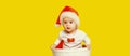 Portrait of happy smiling little child in christmas santa red hat playing with toys on yellow background Royalty Free Stock Photo