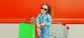 Portrait of happy smiling little girl child with trolley cart and shopping bags wearing denim clothes on city street Royalty Free Stock Photo