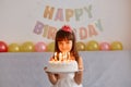 Portrait of happy smiling little girl standing holding cake with candles, celebrating birthday, being ready to make wish and Royalty Free Stock Photo