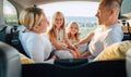 Portrait of happy smiling little sisters. Happy young couple with two daughters inside the car trunk during auto trop. They are Royalty Free Stock Photo