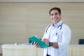 happy smiling male doctor white coat holding folder document standing at counter hospital. Royalty Free Stock Photo