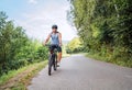 Portrait of a happy smiling man dressed in cycling clothes, helmet and sunglasses riding a bicycle on the asphalt out-of-town Royalty Free Stock Photo