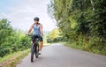 Portrait of a happy smiling man dressed in cycling clothes, helmet and sunglasses riding a bicycle on the asphalt out-of-town Royalty Free Stock Photo