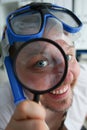 Portrait of a happy smiling manager in swimming goggles looks through magnifying glass Royalty Free Stock Photo