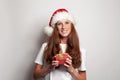 Portrait of happy smiling mature woman in Christmas hat holding red gift box on white studio wall background Royalty Free Stock Photo