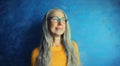 Portrait of happy smiling middle-aged woman in eyeglasses looking away. Senior blonde woman in casual on blue background Royalty Free Stock Photo