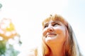 Portrait happy smiling middle aged woman with long blond hair on blurred background of sun light Royalty Free Stock Photo