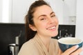 Portrait of happy, smiling modern woman, starts her day with morning mug of tea. Girl drinking coffee in the kitchen Royalty Free Stock Photo