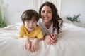 Portrait of happy mom and kid son lying in bed cheerful at first holiday morning relaxing together