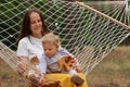 Portrait of happy smiling mother and child relaxing in hammock in forest, mom and daughter playing wooden eco toys, spending Royalty Free Stock Photo