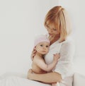 Portrait of happy smiling mother and cute little baby in white room at home Royalty Free Stock Photo