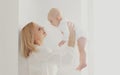 Portrait of happy smiling mother and cute little baby in white room at home Royalty Free Stock Photo