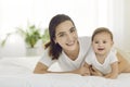 Portrait of a happy, smiling mother and her sweet, cute baby lying on a bed together Royalty Free Stock Photo