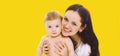 Portrait of happy smiling mother holding her baby isolated on yellow background Royalty Free Stock Photo