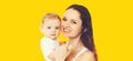 Portrait of happy smiling mother holding her baby isolated on yellow background Royalty Free Stock Photo