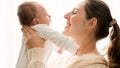 Portrait of happy smiling mother holding and stroking her little newborn baby boy against bright sun shining through Royalty Free Stock Photo